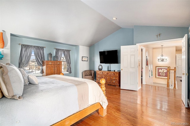 bedroom featuring vaulted ceiling, a chandelier, and hardwood / wood-style floors