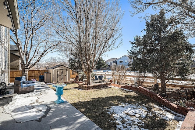 yard layered in snow with a patio and a storage unit