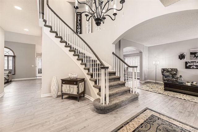 foyer with arched walkways, stairway, healthy amount of natural light, wood finished floors, and recessed lighting
