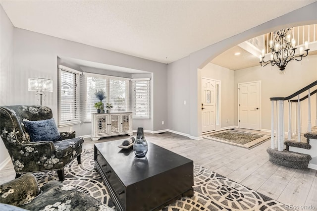 living area with arched walkways, wood finished floors, stairs, and baseboards