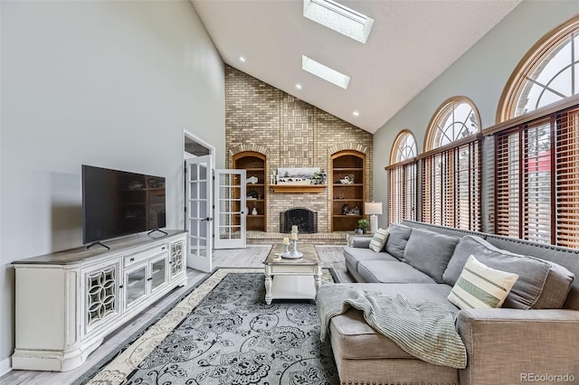 living area with high vaulted ceiling, wood finished floors, a skylight, a brick fireplace, and recessed lighting