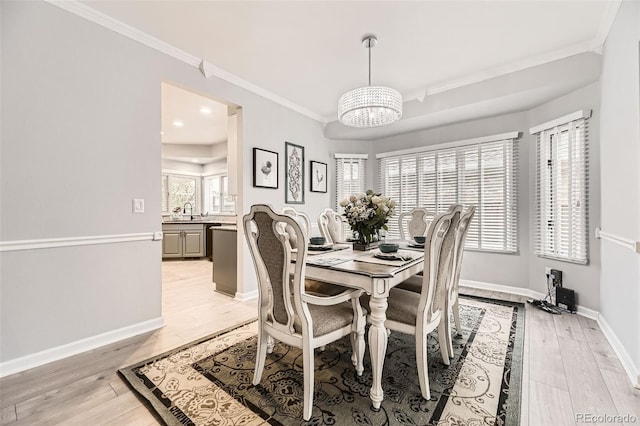dining space featuring a chandelier, crown molding, light wood finished floors, and baseboards