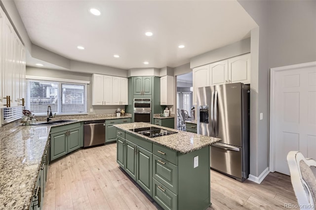 kitchen with green cabinets, appliances with stainless steel finishes, a sink, a kitchen island, and white cabinetry