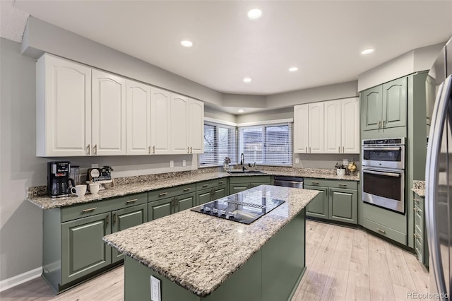 kitchen featuring green cabinetry, a sink, appliances with stainless steel finishes, white cabinetry, and a kitchen island