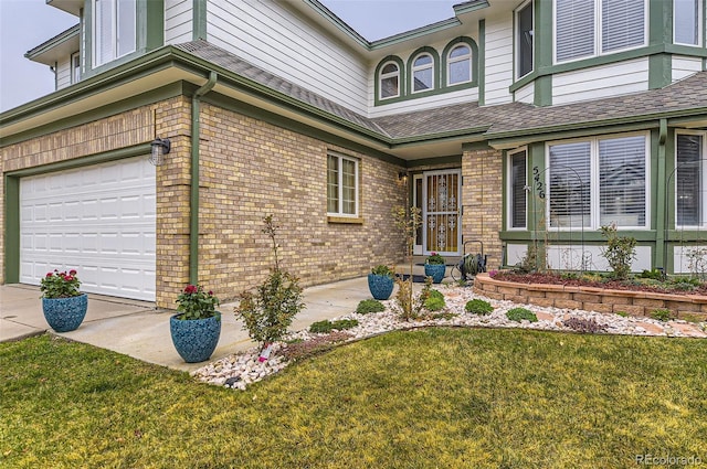 entrance to property with an attached garage, brick siding, and a lawn