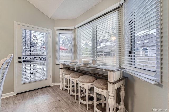 dining space with lofted ceiling, wood finished floors, and baseboards