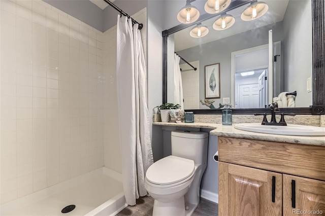 full bath featuring toilet, wood finished floors, vanity, and a tile shower