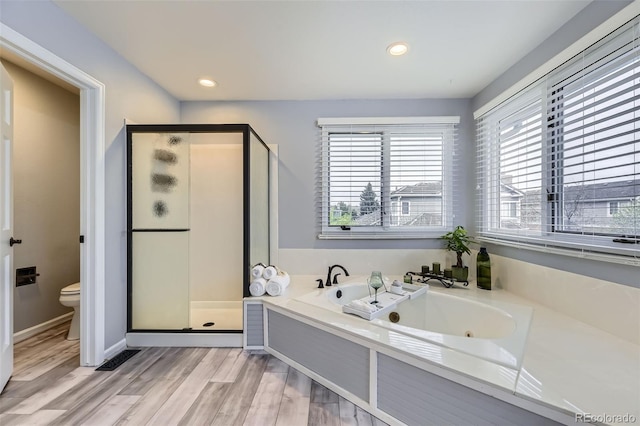 bathroom with a shower stall, a tub with jets, wood finished floors, toilet, and recessed lighting