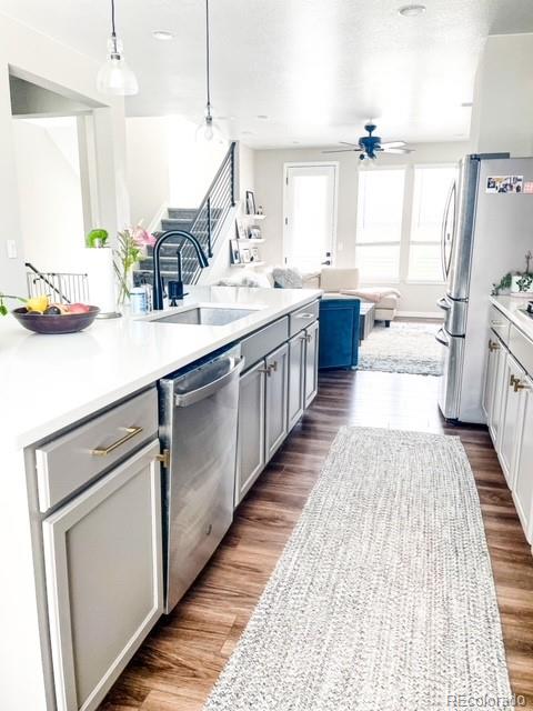 kitchen featuring gray cabinetry, sink, dark hardwood / wood-style flooring, pendant lighting, and appliances with stainless steel finishes