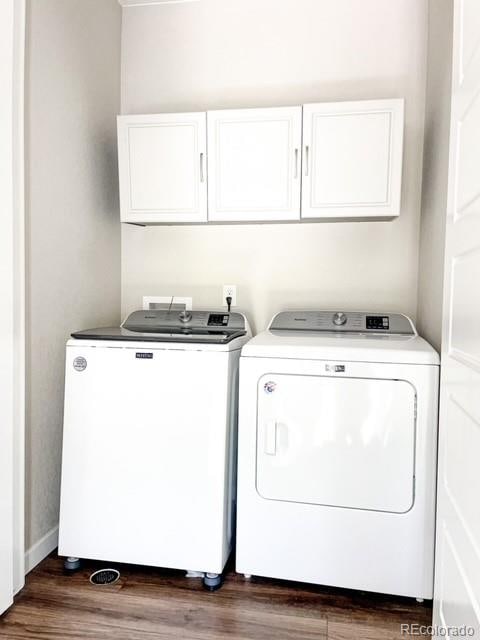 laundry room featuring washing machine and dryer, dark hardwood / wood-style floors, and cabinets