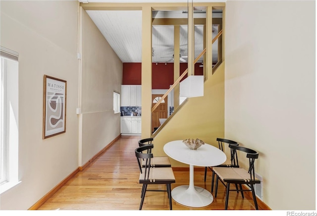 dining room with light wood-style floors, stairway, and a towering ceiling