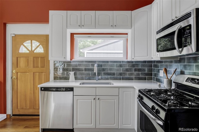 kitchen featuring appliances with stainless steel finishes, white cabinets, light countertops, backsplash, and light wood finished floors