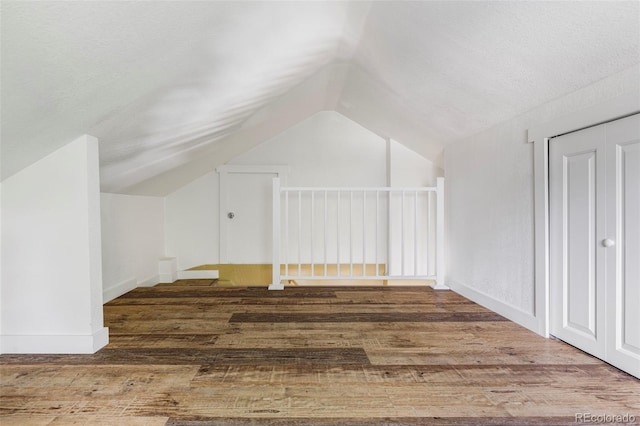 additional living space featuring vaulted ceiling and wood finished floors