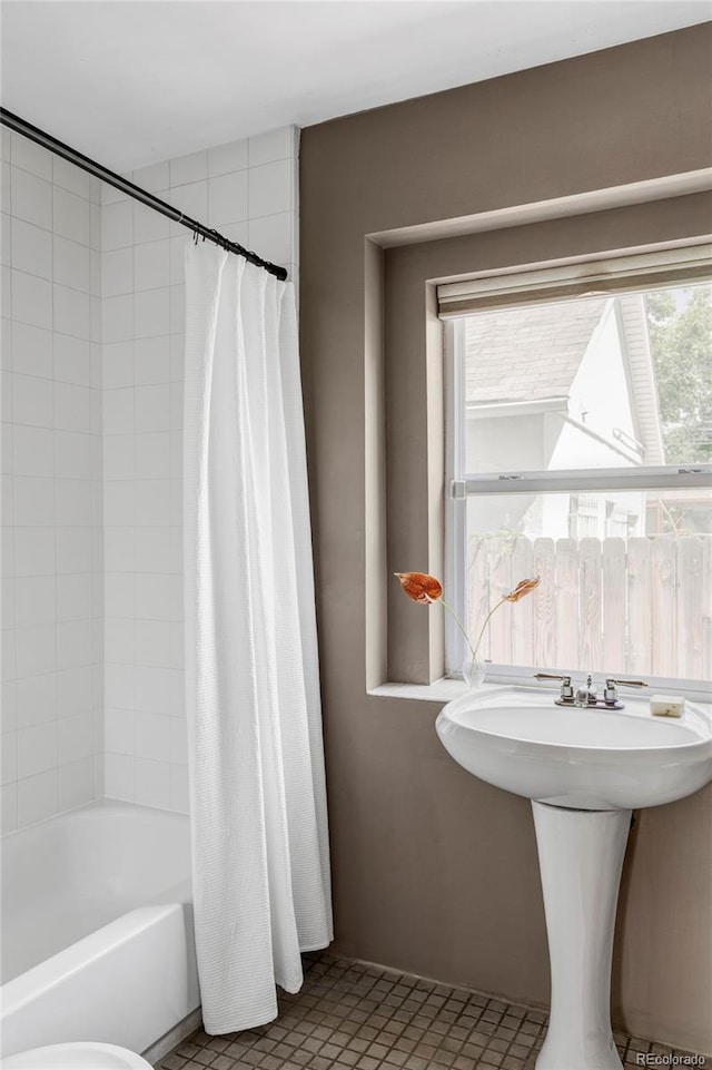 bathroom with shower / bath combination with curtain and a sink