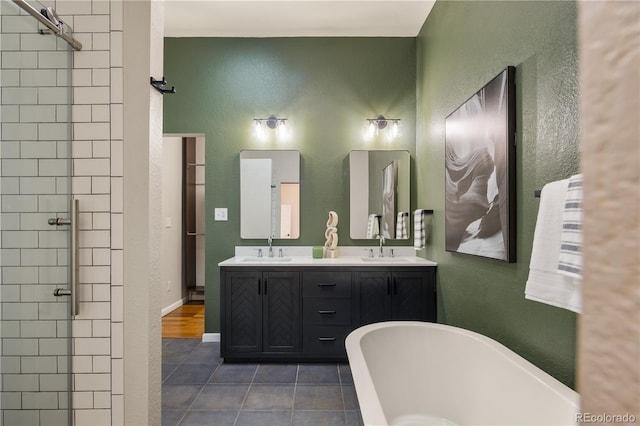 2355 N Emerson St, Denver, CO 80205 - bathroom featuring a freestanding bath, tile patterned flooring, a textured wall, tiled shower, and double vanity