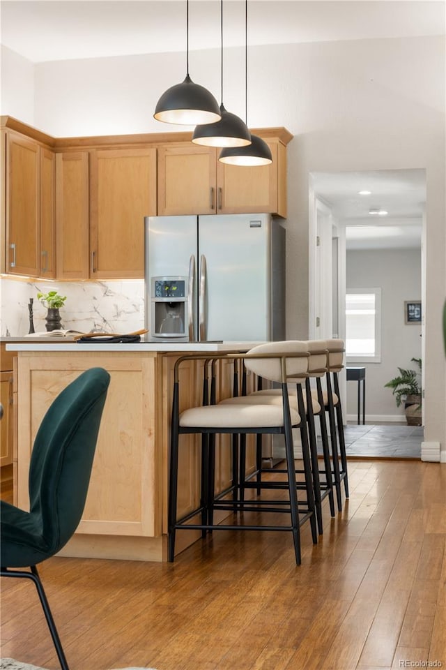 2355 N Emerson St, Denver, CO 80205 - kitchen with light wood-style flooring, pendant lighting, a breakfast bar, tasteful backsplash, and light countertops