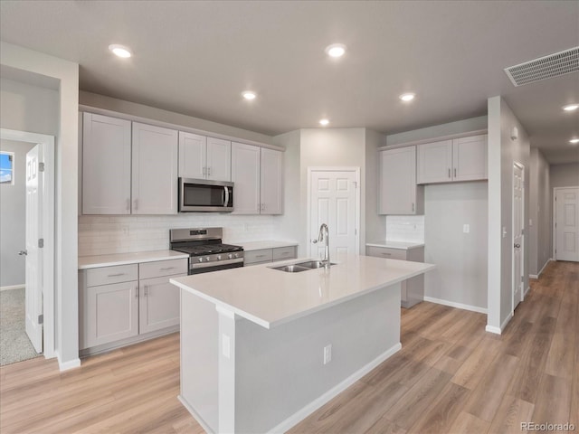 17557 E 89th Way, Commerce City, CO 80022 - kitchen with appliances with stainless steel finishes, decorative backsplash, light wood-style flooring, a center island with sink, and recessed lighting
