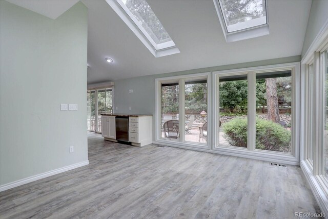 7715 S Hudson Ct, Centennial, CO 80122 - unfurnished living room with lofted ceiling, a skylight, light wood-style flooring, and baseboards