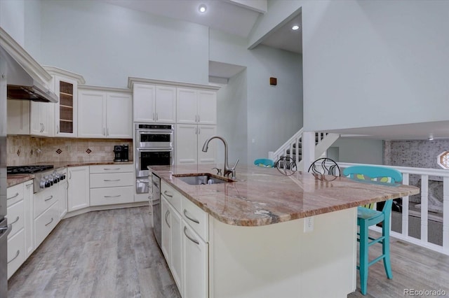 7715 S Hudson Ct, Centennial, CO 80122 - kitchen with a sink, stainless steel appliances, extractor fan, a kitchen breakfast bar, and light wood-style flooring