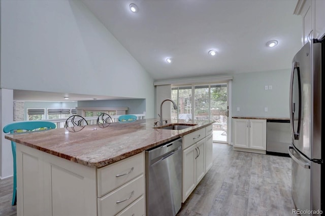7715 S Hudson Ct, Centennial, CO 80122 - kitchen featuring stainless steel appliances, a sink, light wood finished floors, lofted ceiling, and light stone counters