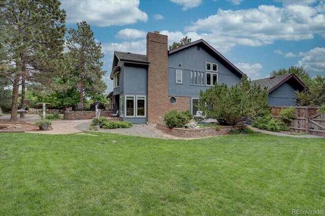7715 S Hudson Ct, Centennial, CO 80122 - back of property with a chimney, a patio area, and brick siding