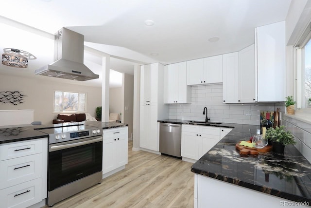 kitchen featuring backsplash, light wood-style flooring, appliances with stainless steel finishes, wall chimney exhaust hood, and a sink