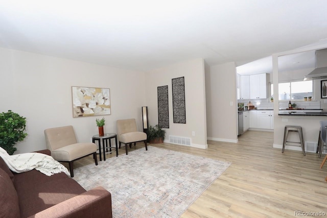 living area featuring light wood finished floors, visible vents, and baseboards