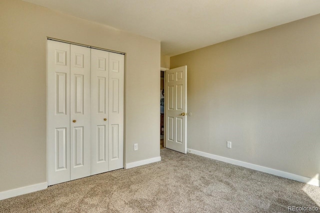 unfurnished bedroom with carpet flooring, baseboards, and a closet