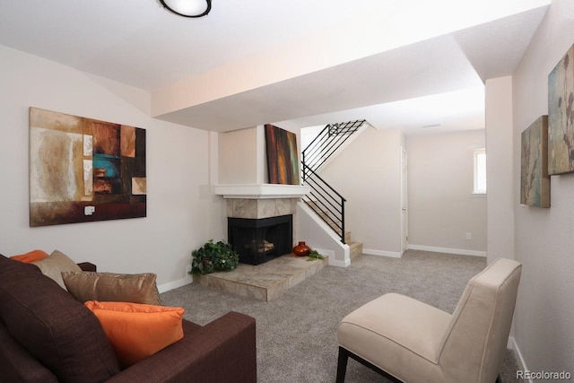 living room with a tiled fireplace, stairway, baseboards, and carpet floors