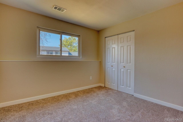 unfurnished bedroom with visible vents, baseboards, a closet, and carpet flooring