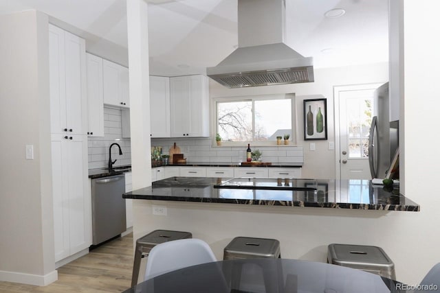 kitchen with a wealth of natural light, a breakfast bar, tasteful backsplash, range hood, and stainless steel appliances