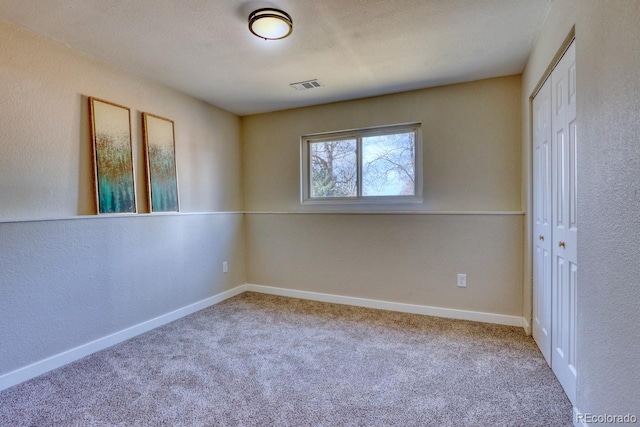 carpeted empty room featuring baseboards and visible vents