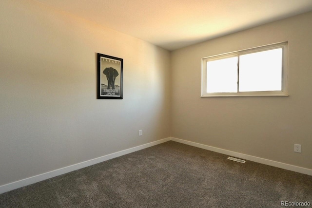 unfurnished room with visible vents, baseboards, and dark colored carpet