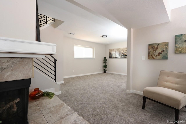 living area featuring visible vents, carpet floors, baseboards, a fireplace, and stairs