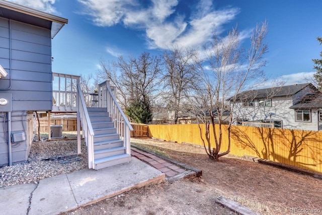 view of yard featuring a deck, stairway, fence private yard, and central AC