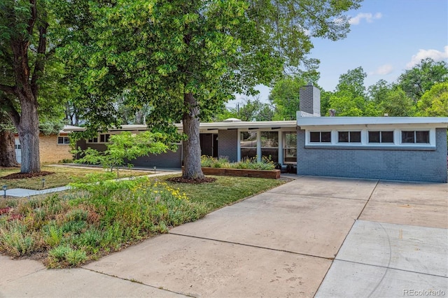6057 S Windermere Way, Littleton, CO 80120 - view of front facade featuring a chimney, brick siding, and driveway