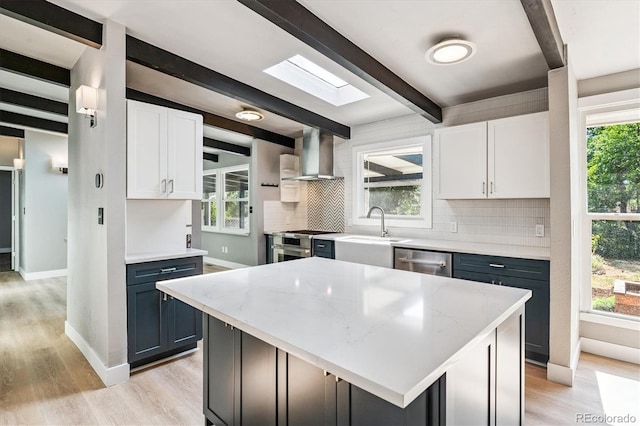 6057 S Windermere Way, Littleton, CO 80120 - kitchen featuring wall chimney range hood, decorative backsplash, beamed ceiling, stainless steel appliances, and light wood-type flooring