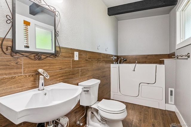 6057 S Windermere Way, Littleton, CO 80120 - bathroom featuring washer / dryer, wood finished floors, a tub to relax in, and tile walls