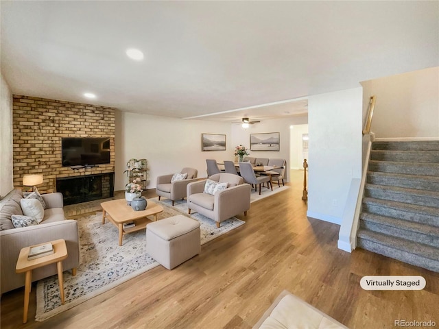 living room with wood-type flooring, ceiling fan, and a fireplace