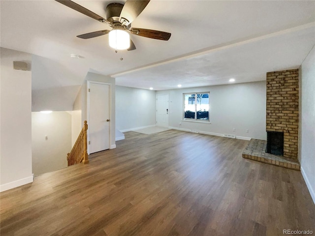 unfurnished living room featuring a fireplace, dark wood-type flooring, and ceiling fan