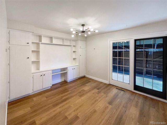 interior space featuring a chandelier, built in desk, and light wood-type flooring