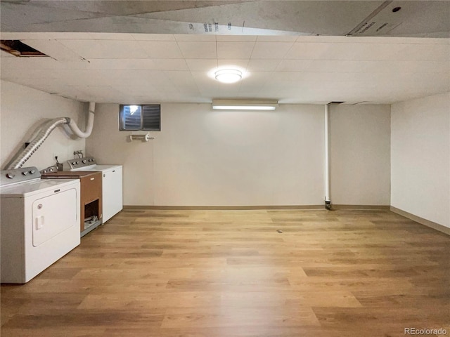 clothes washing area with light hardwood / wood-style flooring and washer and clothes dryer