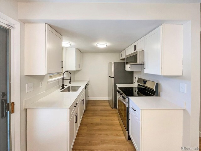 kitchen with white cabinetry, sink, stainless steel appliances, and light hardwood / wood-style floors