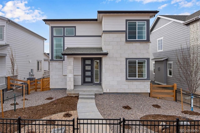 view of front facade with stone siding and fence private yard