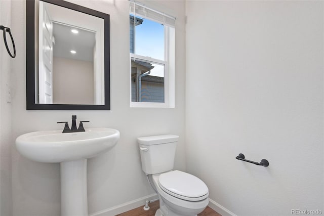 half bathroom featuring toilet, baseboards, and wood finished floors