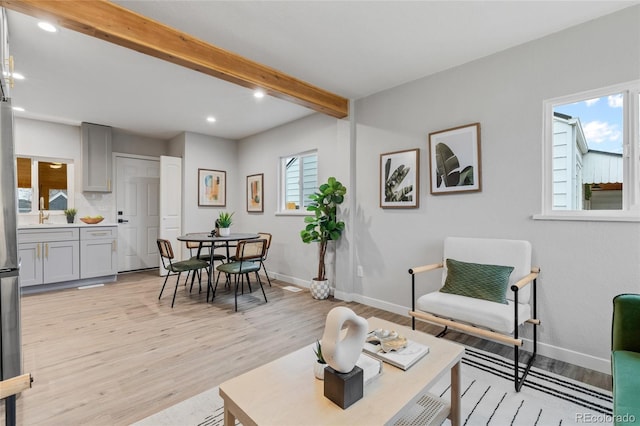 living room featuring beamed ceiling and light hardwood / wood-style floors