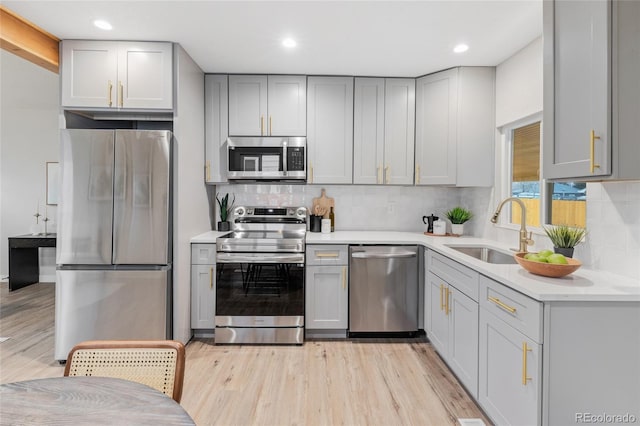 kitchen featuring stainless steel appliances, light hardwood / wood-style flooring, gray cabinetry, and sink