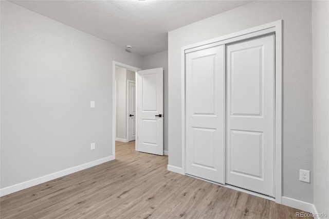 unfurnished bedroom with a closet and light wood-type flooring