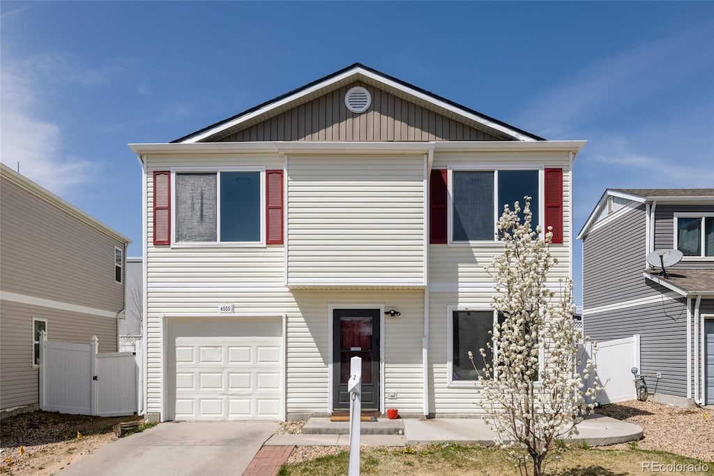 view of front of house with concrete driveway, a garage, fence, and a gate