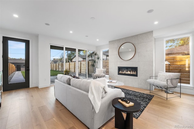 living room with a fireplace, light hardwood / wood-style floors, and tile walls